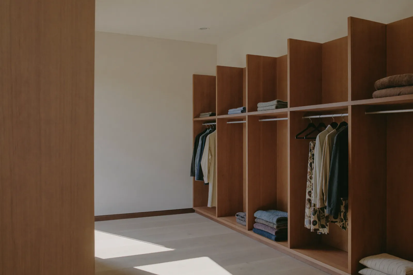Dressing en noyer sur mesure, étagères ouvertes et penderies, éclairage indirect