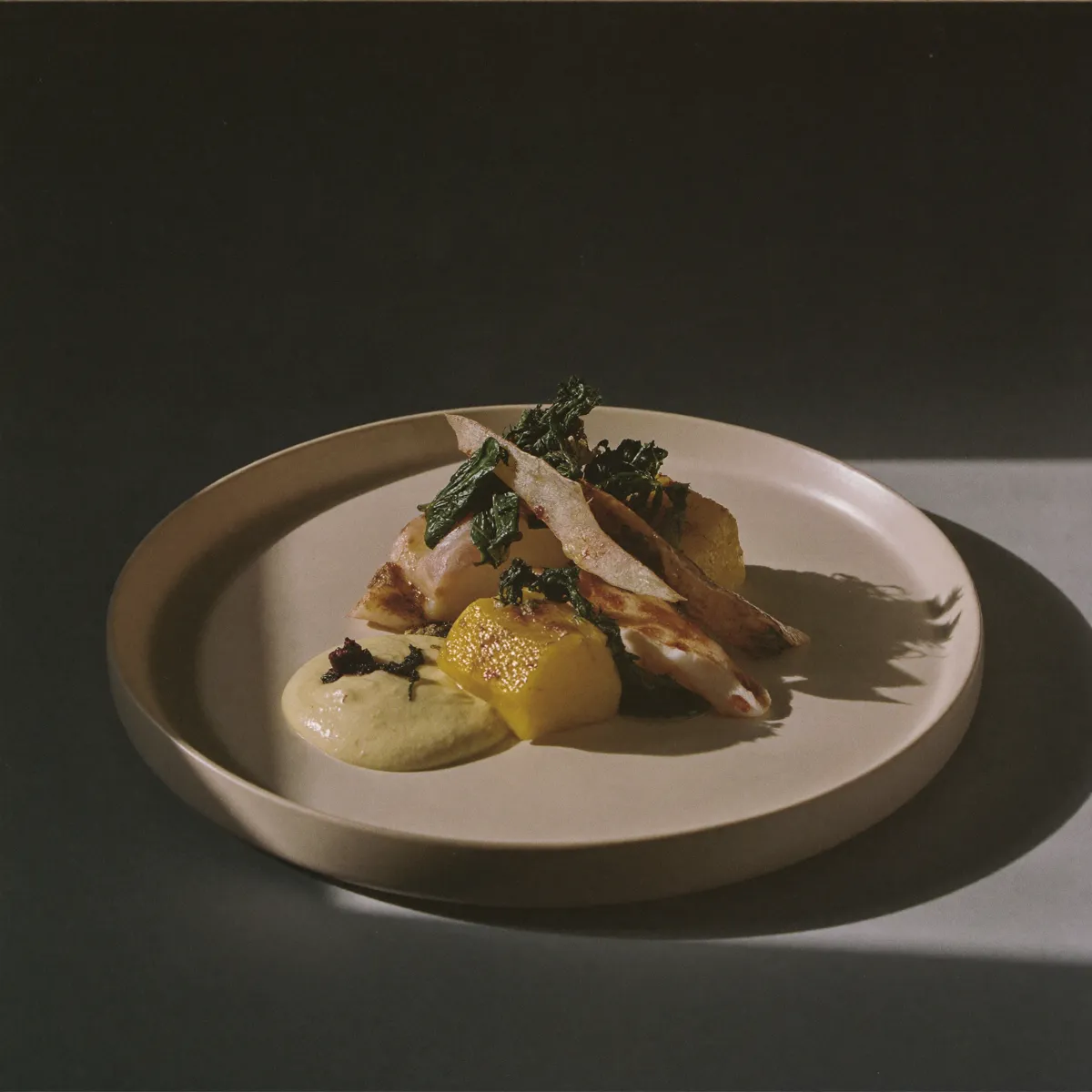 Lieu jaune nacré, algues et beurre fumé, dressage sobre sur assiette crème